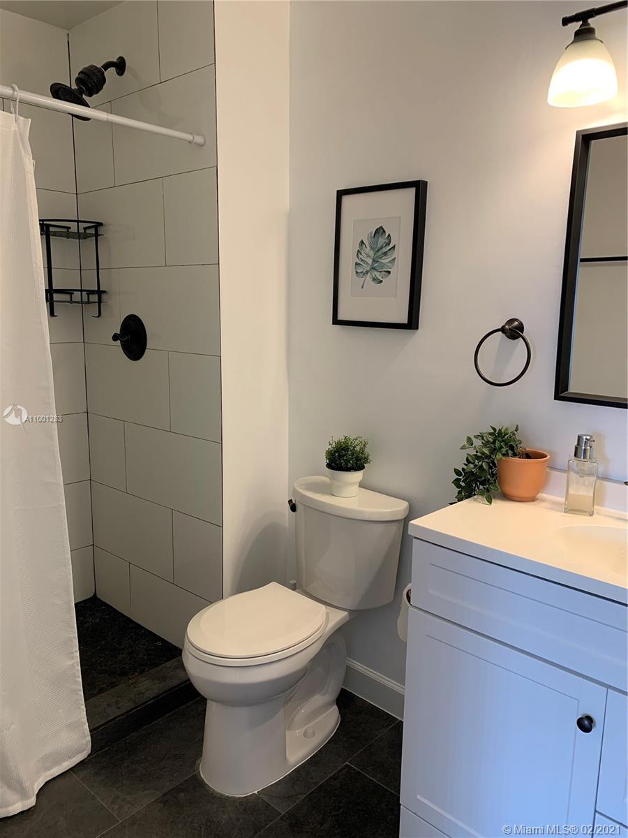 a bathroom with a granite countertop toilet a sink and shower
