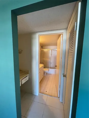 a view of a hallway with wooden floor and a bathroom