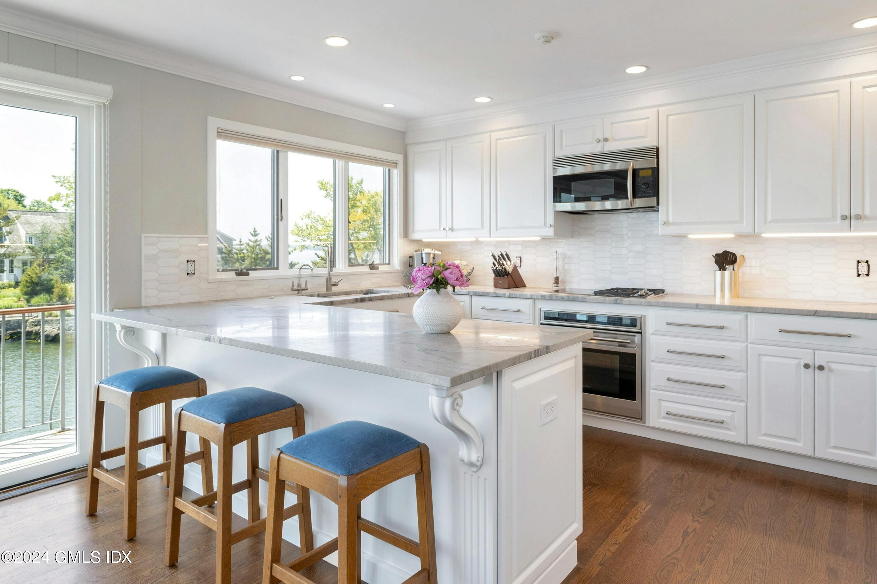 36-38 Game Cock Road Greenwich, CT 06830 - Photo 17 of 34 a kitchen with stainless steel appliances kitchen island granite countertop a stove a sink a dining table and chairs