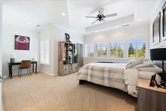 a spacious bedroom with a bed a chandelier and a couch