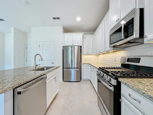 a kitchen with stainless steel appliances granite countertop a refrigerator and a stove top oven
