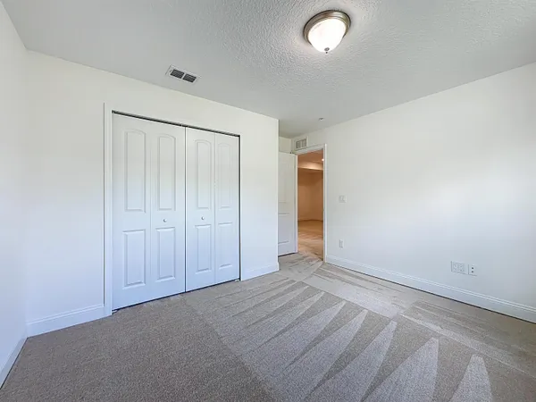an empty room with wooden floor chandelier fan and windows