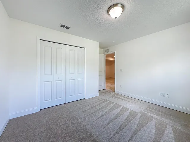 an empty room with wooden floor chandelier fan and windows