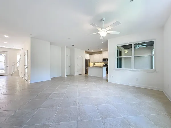 an empty room with windows and chandelier fan