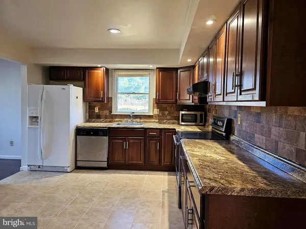 a kitchen with stainless steel appliances granite countertop a stove refrigerator and microwave