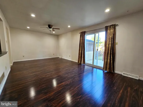 an empty room with wooden floor and a ceiling fan