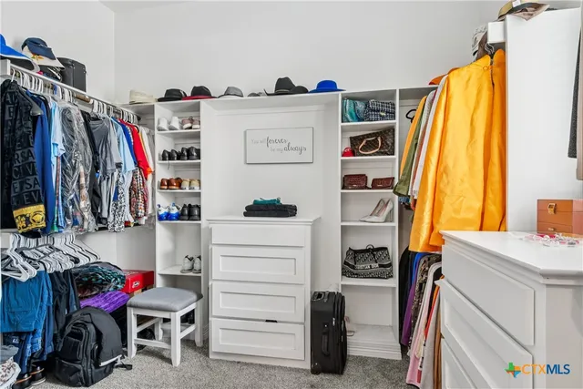 a view of walk in closet with clothes and shoes