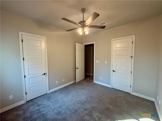 an empty room with closet and a chandelier fan