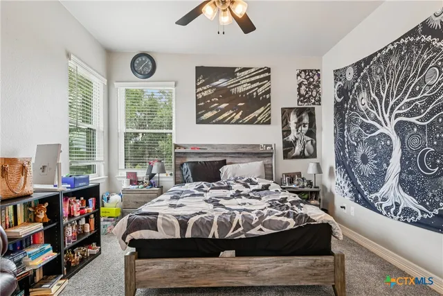 a bedroom with a bed a wall painting and a large window