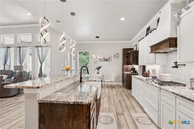 a large kitchen with granite countertop a sink stainless steel appliances and cabinets
