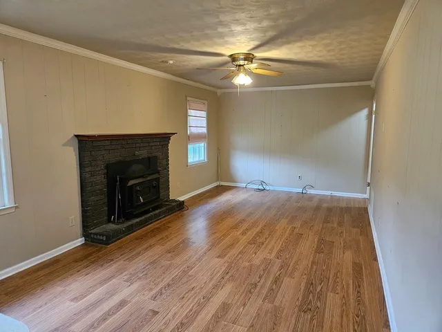 an empty room with wooden floor fireplace and windows