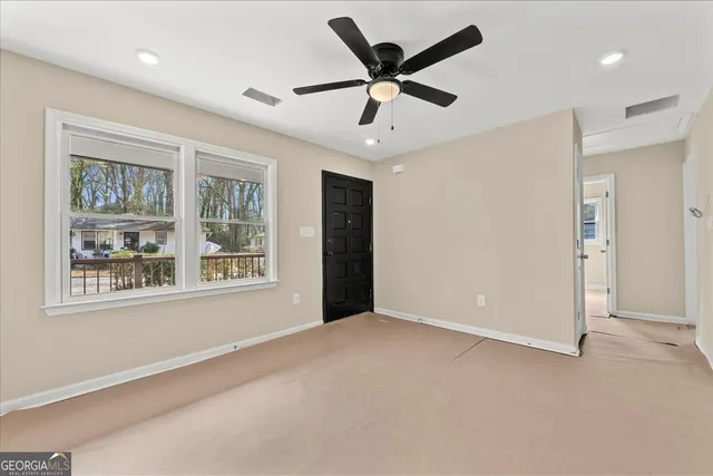 a view of a livingroom with a ceiling fan & windows