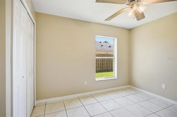 a view of an empty room with a window and a kitchen