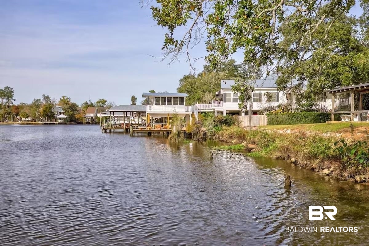 16297 Honey Road Summerdale, AL 36580 - Photo 5 of 24 Waterfront property featuring a private boat dock with covered slip, a spacious screened-in porch, a large elevated deck, and a manicured lawn