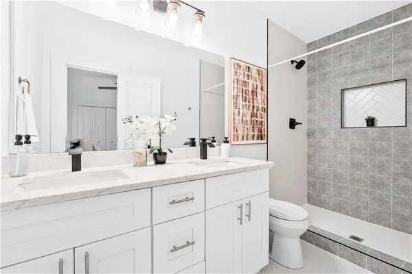 a bathroom with a double vanity sink toilet mirror and shower