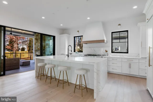 a kitchen with stainless steel appliances granite countertop a stove a sink dishwasher and a dining table with wooden floor