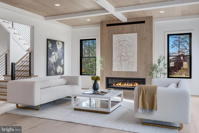 a living room with furniture large window and wall paintings