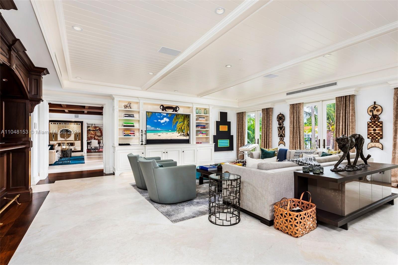 6385 Pine Tree Dr Circle Miami Beach, FL 33140 - Photo 13 of 37 a living room with furniture a flat screen tv and a floor to ceiling window