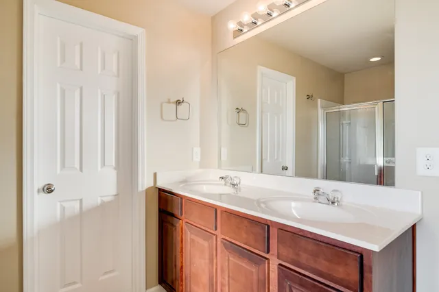 a bathroom with a double vanity sink toilet mirror and shower