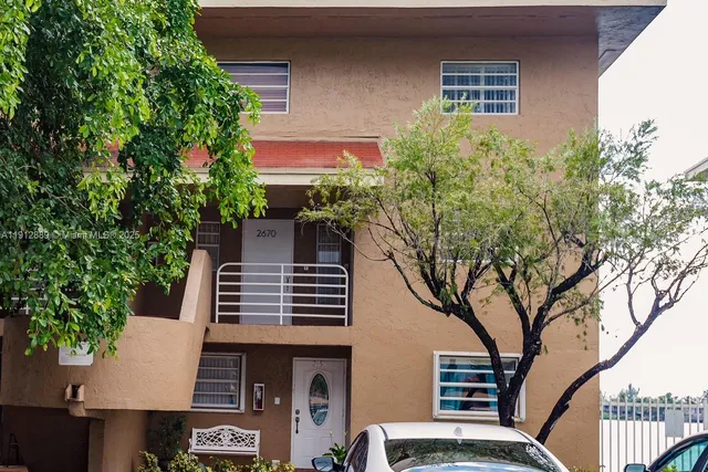 a front view of a house with plants and trees
