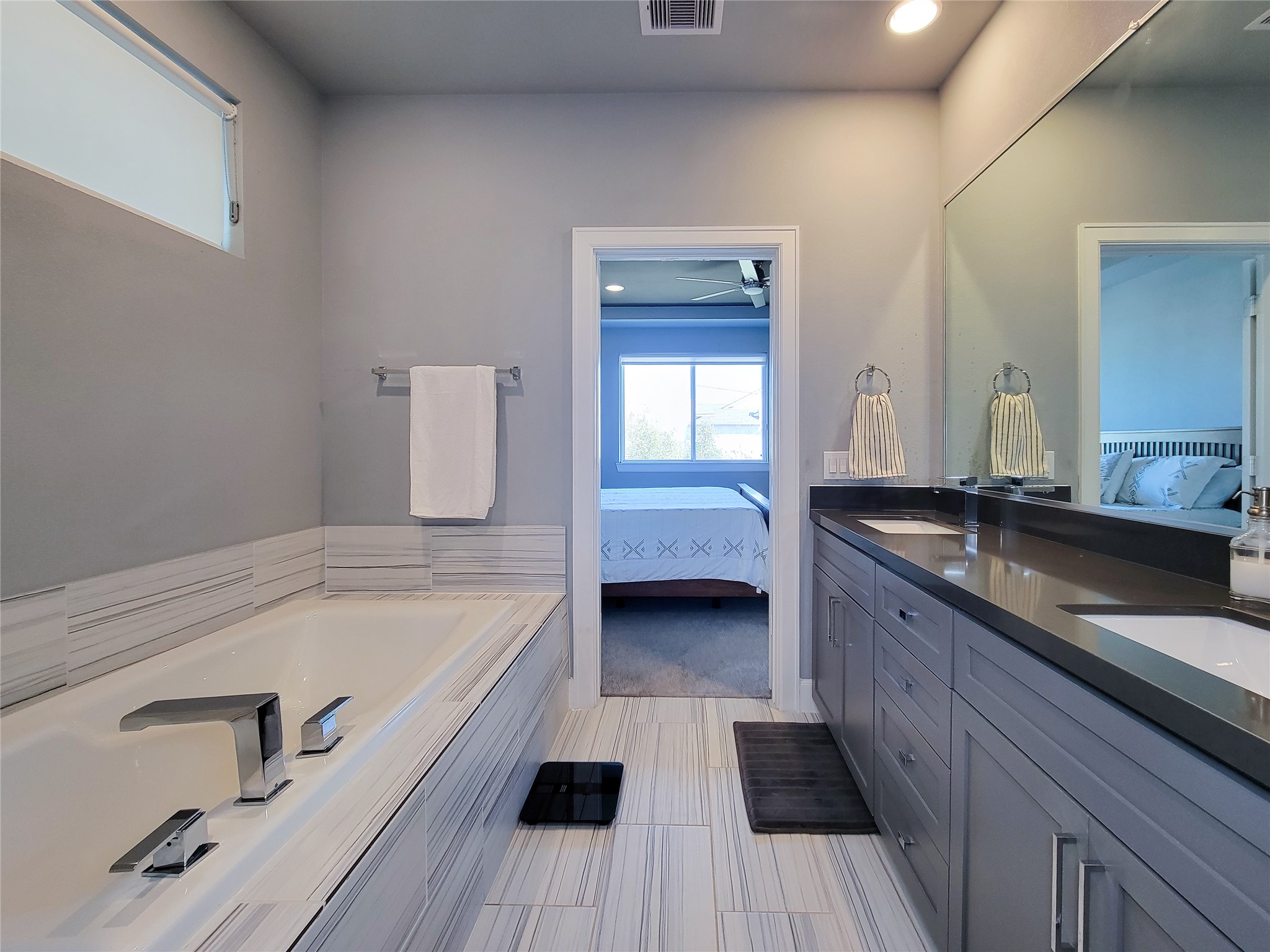 1705 Eado Point Lane Houston, TX 77003 - Photo 45 of 50 Primary bathroom with a sleek design, featuring a large soaking bathtub, a double-sink vanity with ample storage, and a doorway leading to a bedroom.