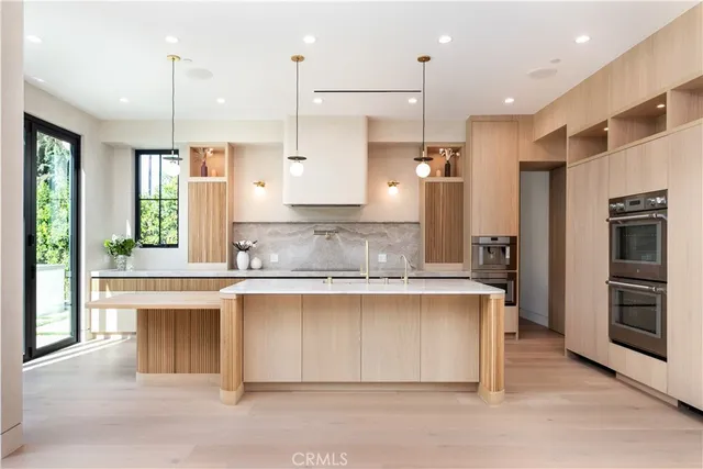 a large kitchen with kitchen island a large counter top a sink stainless steel appliances and cabinets