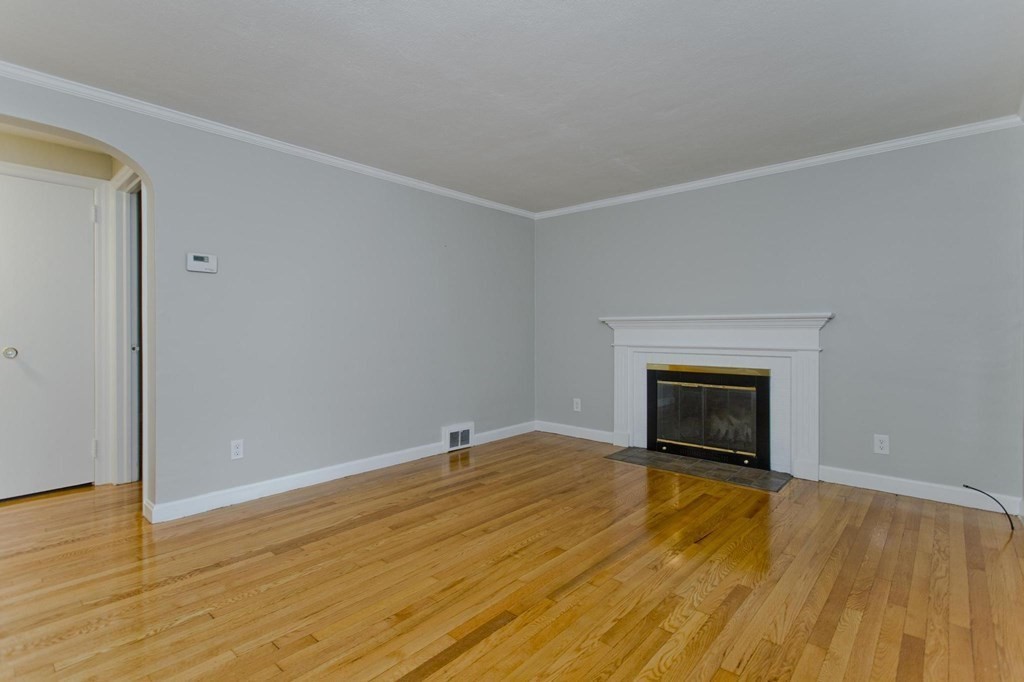 228 Shawmut Street Springfield, MA 01108 - Photo 16 of 39 a view of empty room with wooden floor and fireplace