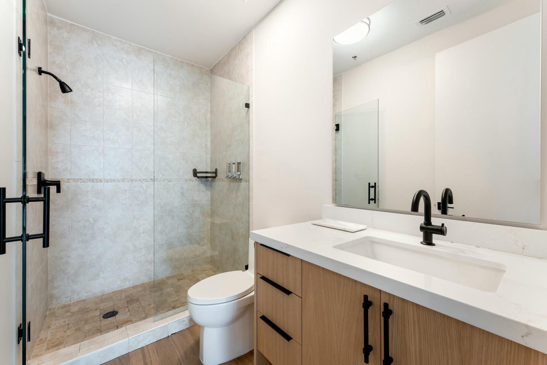 104000 Overseas Highway, Unit 5 Key Largo, FL 33037 - Photo 14 of 60 a bathroom with a granite countertop sink toilet and shower