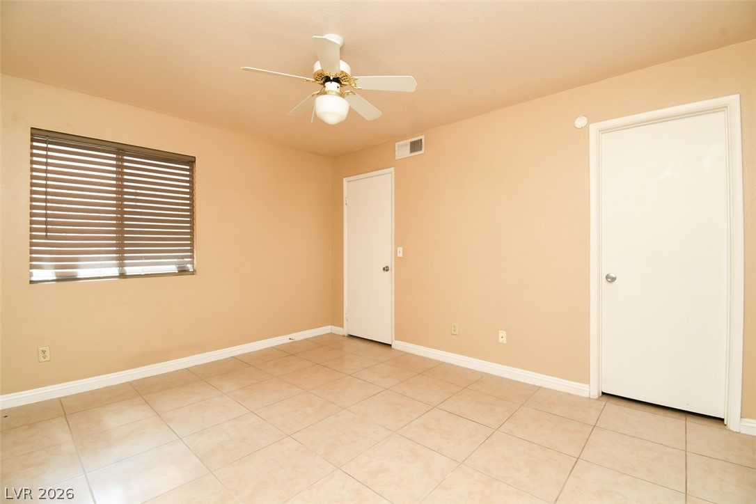 7570 West Flamingo Road, Unit 119 Las Vegas, NV 89147 - Photo 12 of 15 A well-proportioned interior room features a ceiling fan and durable tile flooring, offering versatile living space.