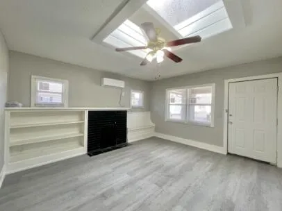 a view of an empty room with a window and a kitchen