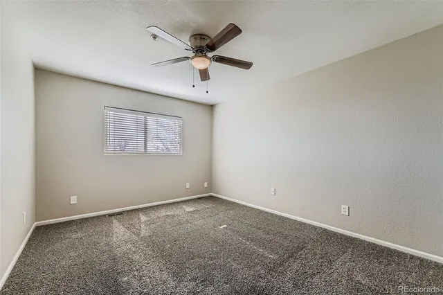 an empty room with a window and a fan