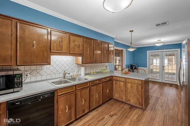 a kitchen with stainless steel appliances granite countertop a refrigerator a sink dishwasher a stove and white countertops with wooden floor