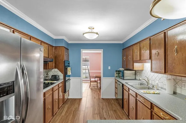 a kitchen with stainless steel appliances kitchen island granite countertop a stove a sink a dining table and chairs with wooden floor