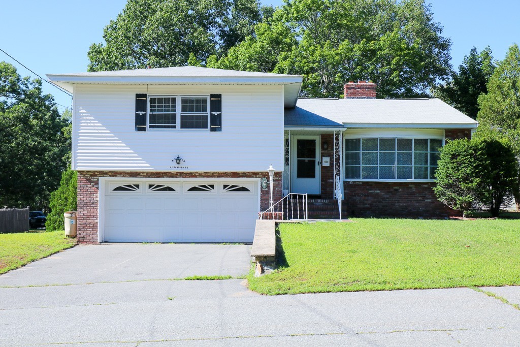a view of a house with a yard potted plants and a table