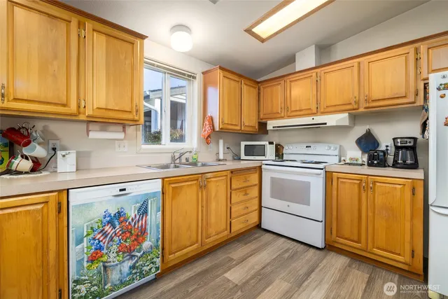 a kitchen with stainless steel appliances granite countertop a stove a sink dishwasher and cabinets with wooden floor