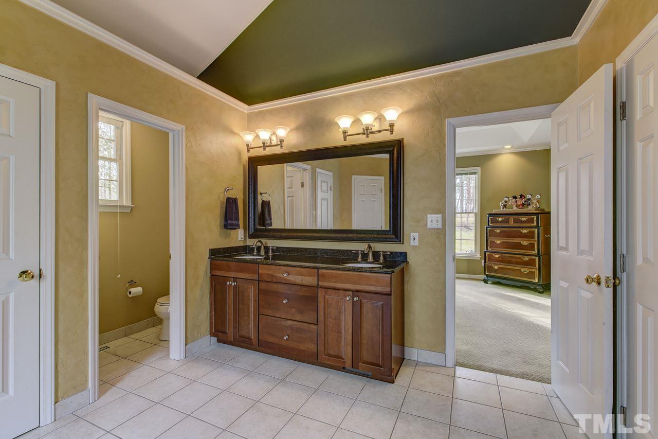 12312 Galway Drive Raleigh, NC 27613 - Photo 14 of 25 The master luxury 2-story spa bath features a double granite vanity with triple globe fixtures, His & Her closets, decorative stucco finish on walls, tile floors, jetted garden tub, walk-in tile surround shower, separate water closet, and ceiling fan.