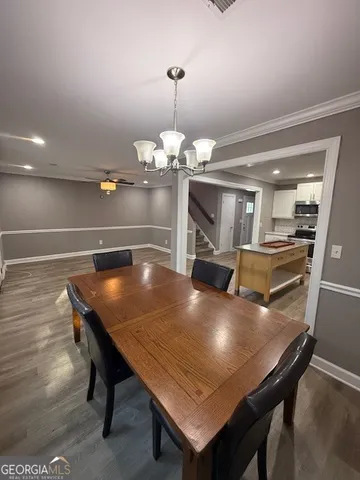 a dining room with wooden floor and chandelier
