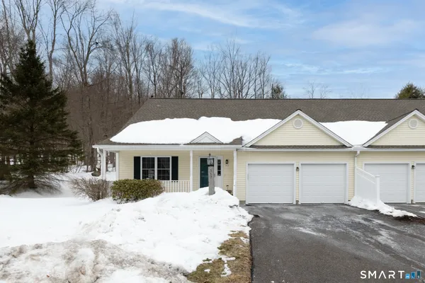 a front view of a house with a yard covered in snow