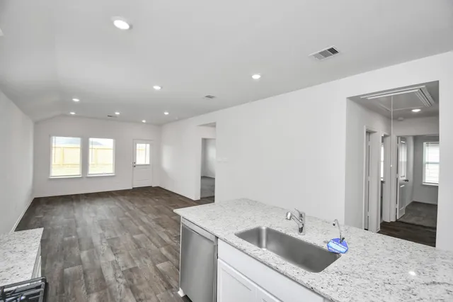 a kitchen with a sink dishwasher and a refrigerator with wooden floor