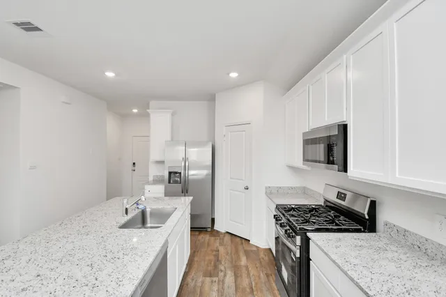 a kitchen with stainless steel appliances granite countertop a sink stove and refrigerator