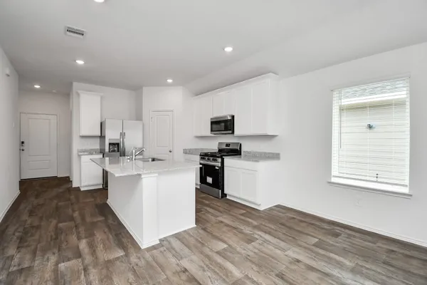 a kitchen with granite countertop a stove top oven sink and cabinets