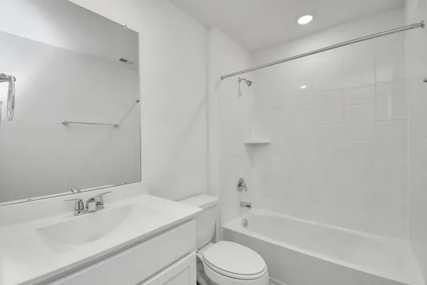 a bathroom with a bathtub shower sink vanity mirror and toilet