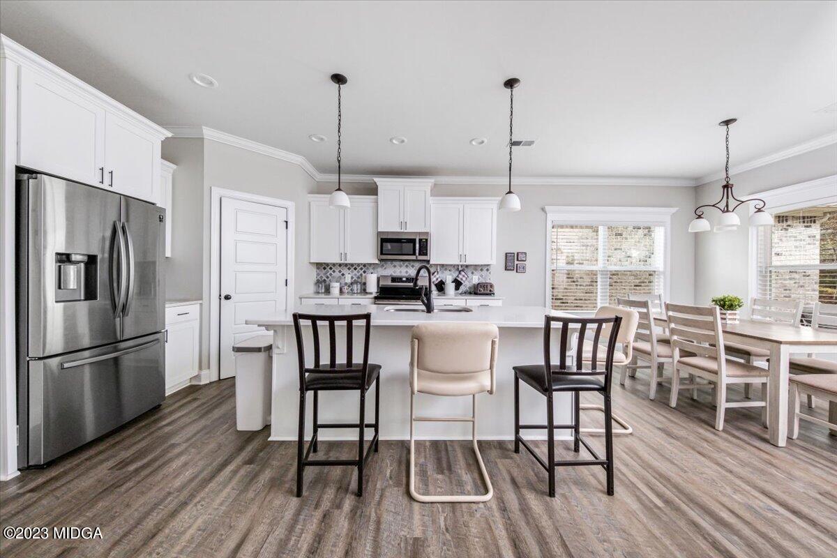 208 Carters Way Forsyth, GA 31029 - Photo 6 of 22 a kitchen with stainless steel appliances granite countertop a dining table chairs refrigerator and microwave