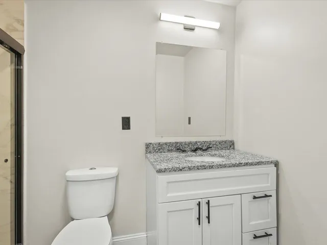 a bathroom with a granite countertop toilet sink and mirror