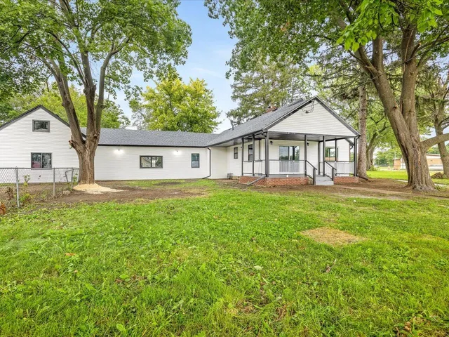 a front view of a house with a garden and trees