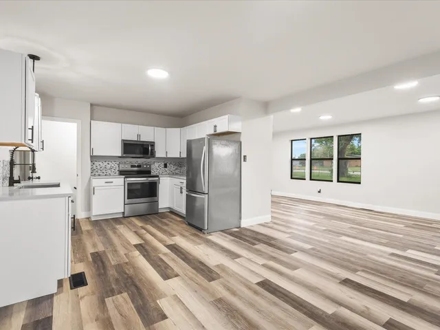 a kitchen with granite countertop a refrigerator and a stove top oven