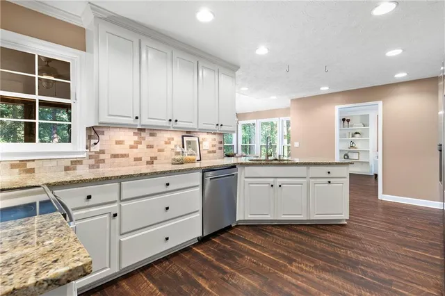 a kitchen with granite countertop white cabinets stainless steel appliances a sink and a window