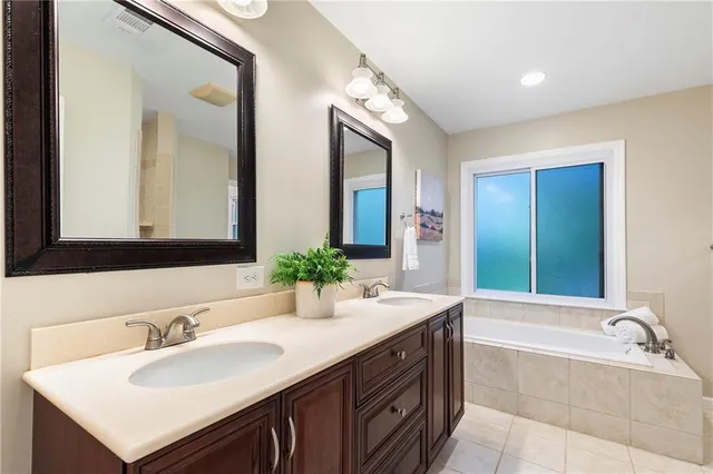 a bathroom with a bathtub double sink and mirror