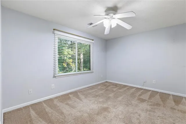 an empty room with a chandelier fan and windows