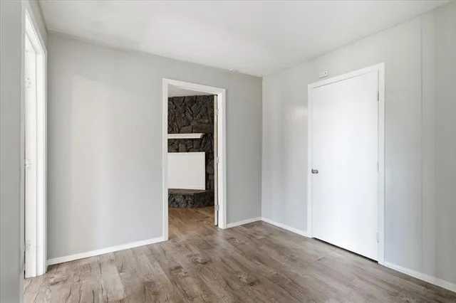 a view of an empty room with wooden floor and closet